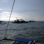 Trois bancas de plongée au mouillage sur Monad Shoal sous un ciel gris de petit matin, vues depuis le pont d'un autre bateau