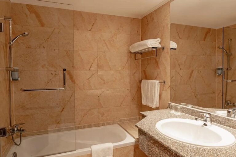 Une salle de bains en marbre avec baignoire, douche et lavabo