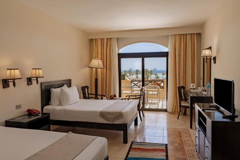 Une chambre à deux lits avec télévision, bureau et balcon face à la mer