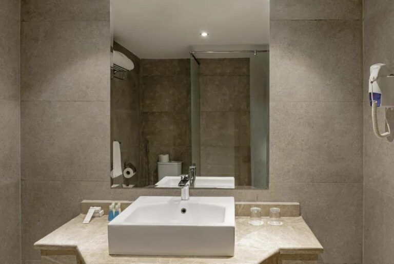Une salle de bains avec vasque carrée, grand miroir et sèche-cheveux