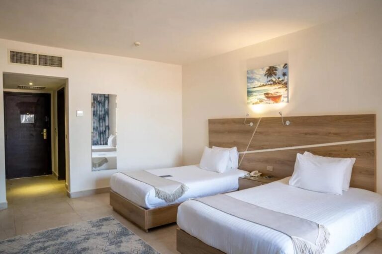 Une chambre à deux lits avec une tête de lit en bois clair et un tableau de plage