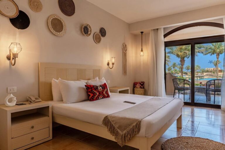 Une chambre au grand lit décorée de paniers tressés, ouverte sur une terrasse et la piscine