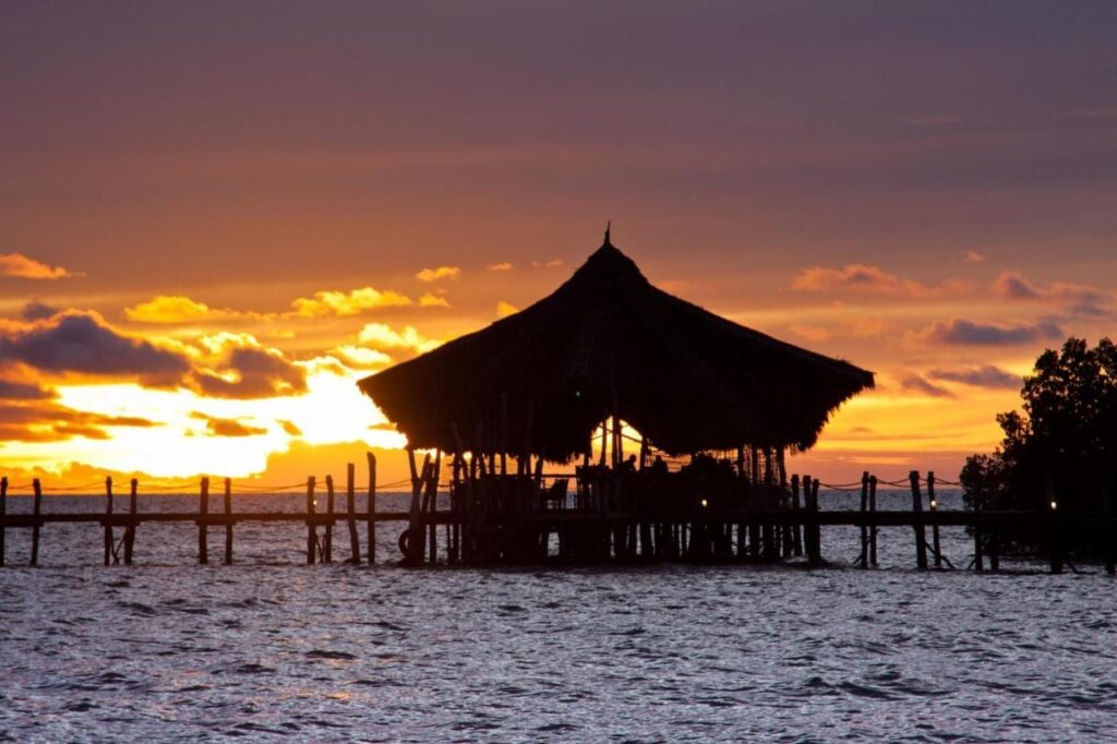 Le pavillon au toit de paille du Fundu Lagoon, sur pilotis au bout du ponton, au coucher du soleil