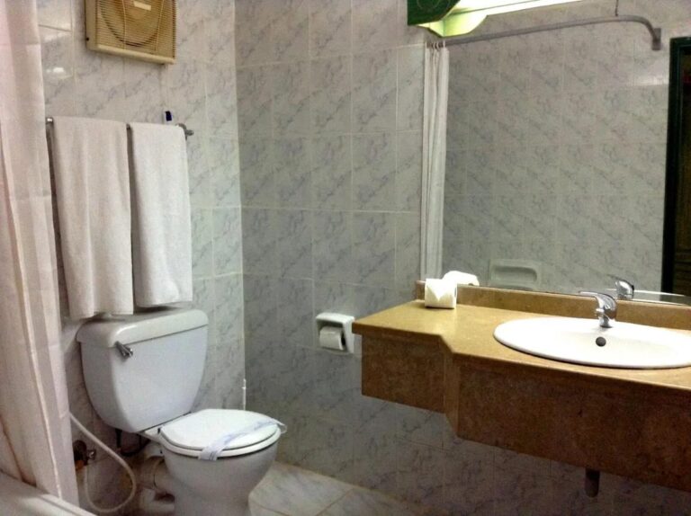 Une salle de bains carrelée de gris, avec un lavabo sur plan et un rideau de douche