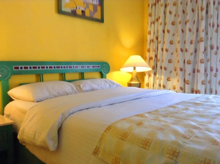 Un lit à tête de lit verte décorée de mosaïque, contre un mur jaune