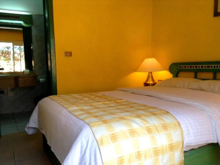 Une chambre aux murs jaunes avec un grand lit et la porte de la salle de bains ouverte