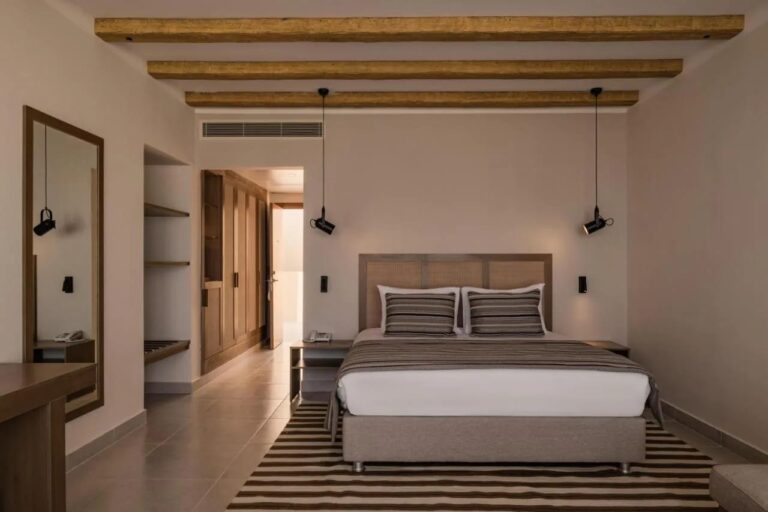 Une chambre au grand lit sous un plafond à poutres apparentes