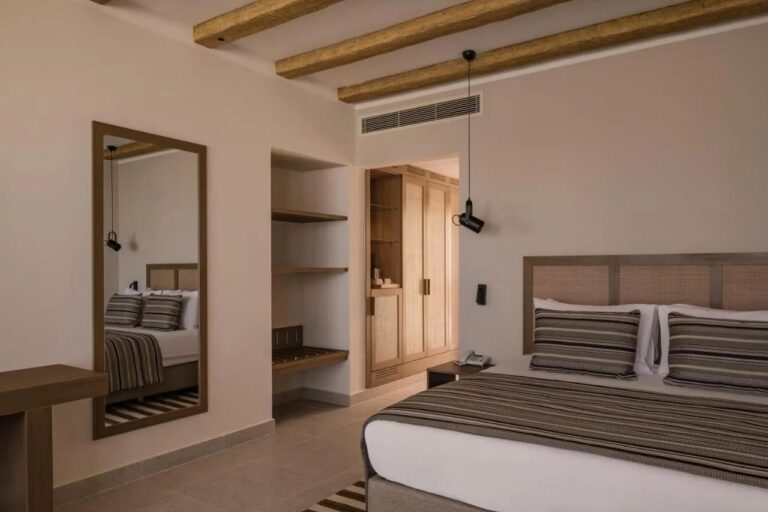 Une chambre au grand lit avec un grand miroir et un dressing ouvert