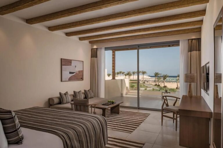 Une chambre avec un coin salon et une baie vitrée face à la mer
