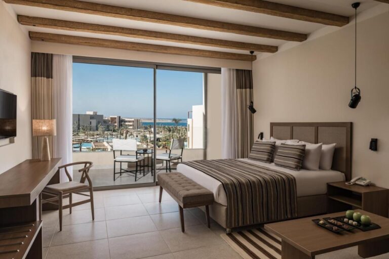 Une chambre au grand lit avec balcon, vue sur les piscines et la mer Rouge
