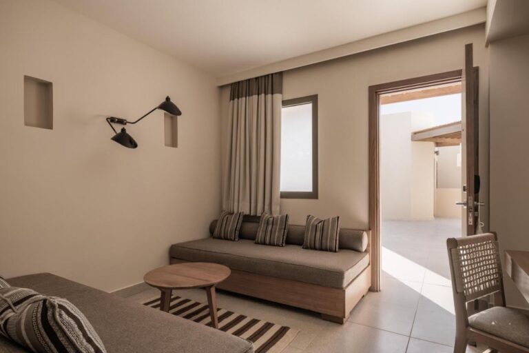 Le coin salon d'une chambre, avec une banquette et une porte ouverte sur l'extérieur