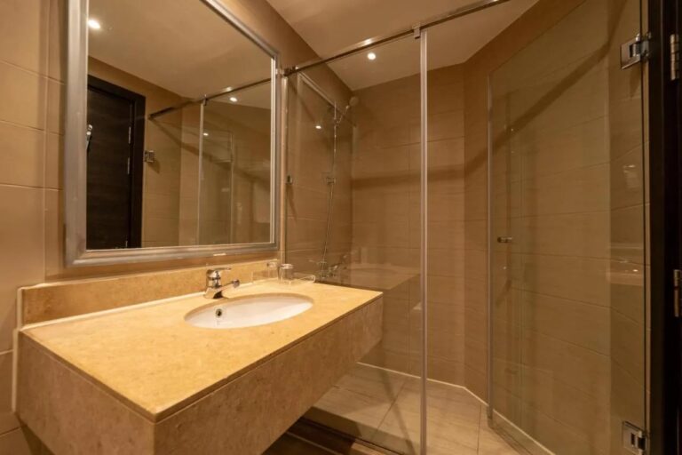 Une salle de bains avec vasque, grand miroir et douche vitrée