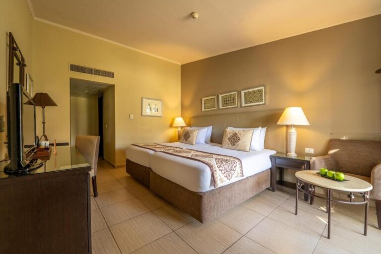 Une chambre à deux lits avec un fauteuil et une table basse garnie de pommes vertes