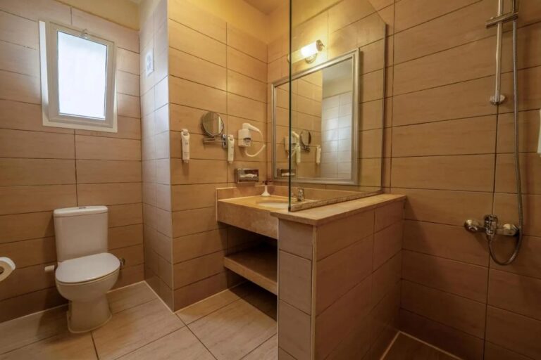 Une salle de bains avec une petite fenêtre, une vasque et une douche derrière une paroi vitrée