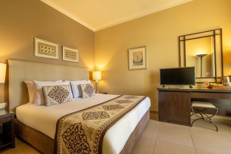 Une chambre au grand lit avec un bureau, une télévision et un grand miroir