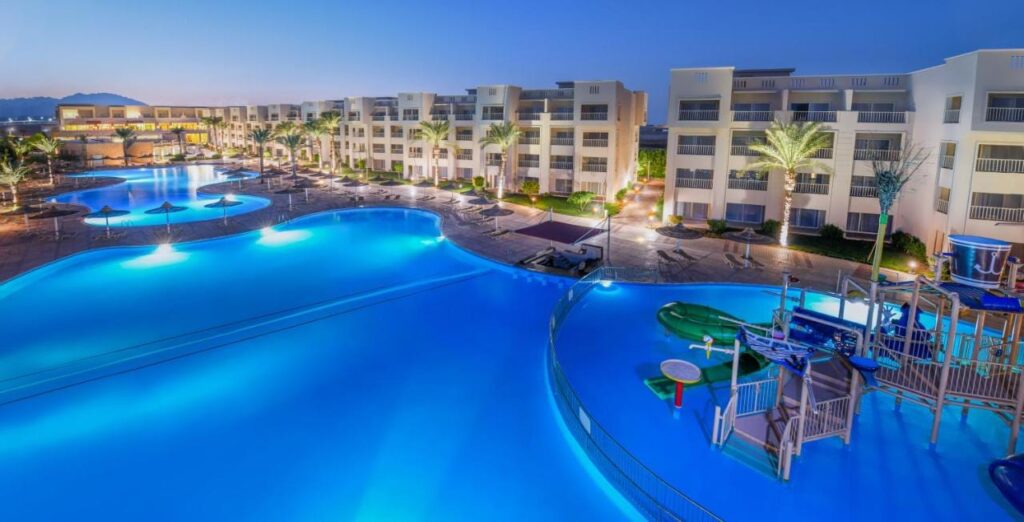 Les piscines éclairées du JAZ Soma Beach à la tombée de la nuit, entre les bâtiments et les palmiers