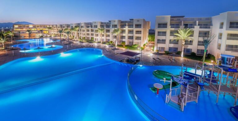 Les piscines éclairées du JAZ Soma Beach à la tombée de la nuit, entre les bâtiments et les palmiers
