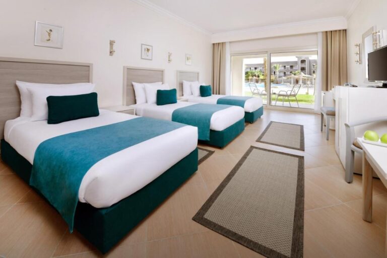 Une chambre à trois lits aux meubles clairs, ouverte sur une terrasse face à la piscine
