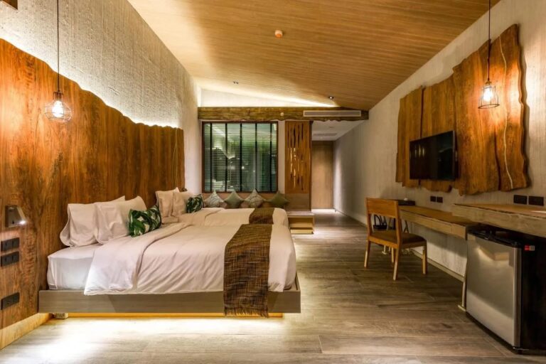 Une chambre à deux lits avec une tête de lit en bois brut, un bureau et un téléviseur