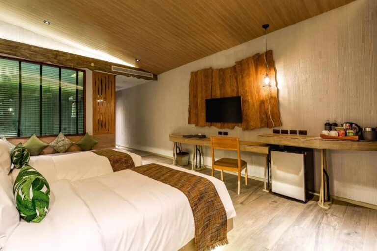 Une chambre à deux lits avec une banquette sous la fenêtre, un bureau et un plateau à thé