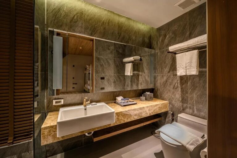 Une salle de bains en pierre grise avec une vasque sur un plan en marbre et un grand miroir