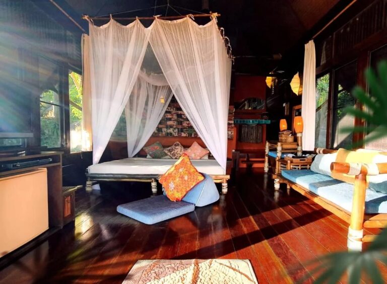 Le lit sous moustiquaire et la banquette d'un cottage, éclairés par le soleil