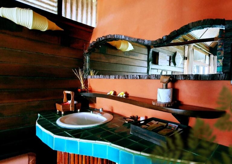 Une vasque sur un comptoir en mosaïque turquoise, sous un miroir encadré de bois