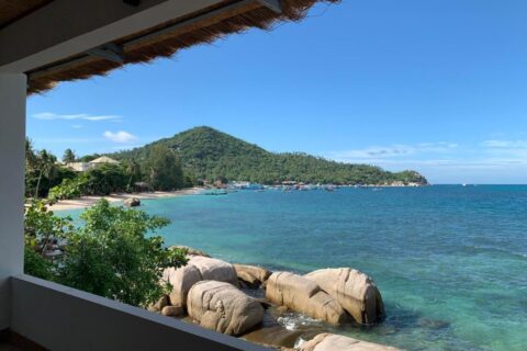 La baie et ses rochers vus d'une terrasse couverte du Koh Tao Heritage, avec des bateaux au mouillage