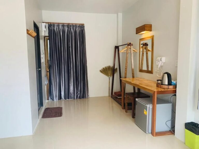 L'entrée d'une chambre, avec un rideau gris, un portant et un bureau en bois