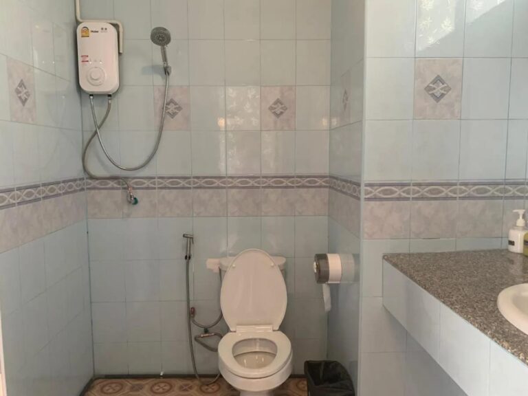 Une salle de bains carrelée avec une douche à chauffe-eau, des toilettes et un lavabo