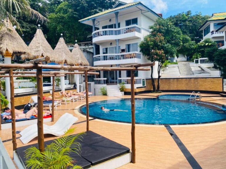 La piscine du Koh Tao Heritage, ses transats et ses parasols de paille, devant un bâtiment à balcons