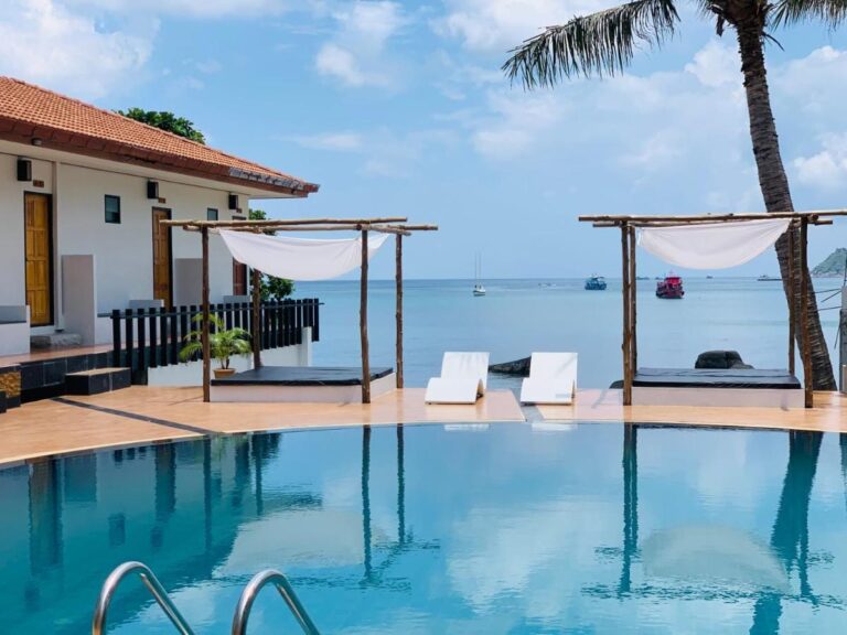 La piscine face à la mer, avec deux lits sous pergola et des transats blancs