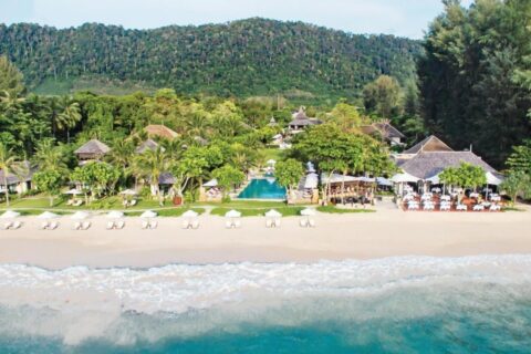 Le Layana Resort vu de la mer, avec sa plage, ses parasols blancs, sa piscine et ses toits sous les palmiers