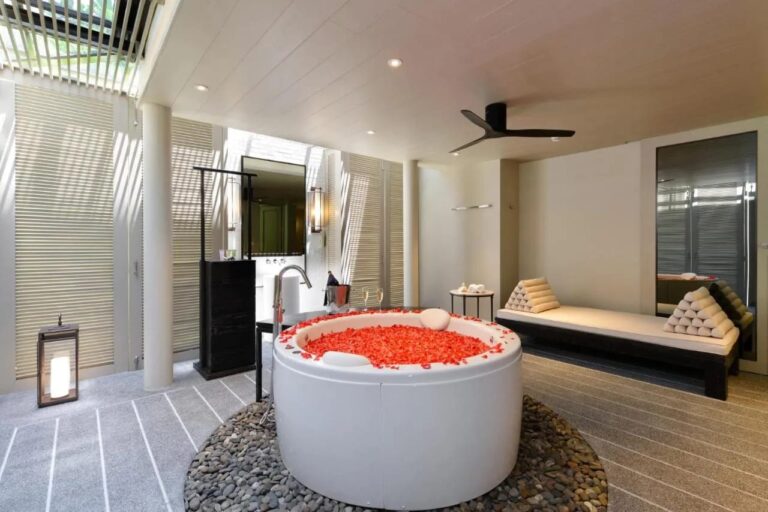 Une baignoire ronde remplie de pétales rouges, posée sur des galets