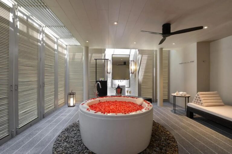 Une salle de bains à persiennes avec une baignoire ronde au centre et une banquette
