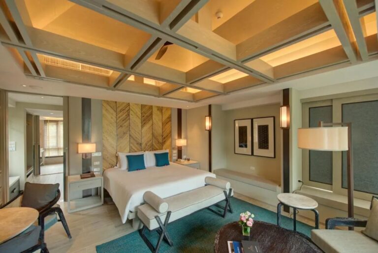 Une chambre au grand lit avec un lampadaire et une banquette sous la fenêtre