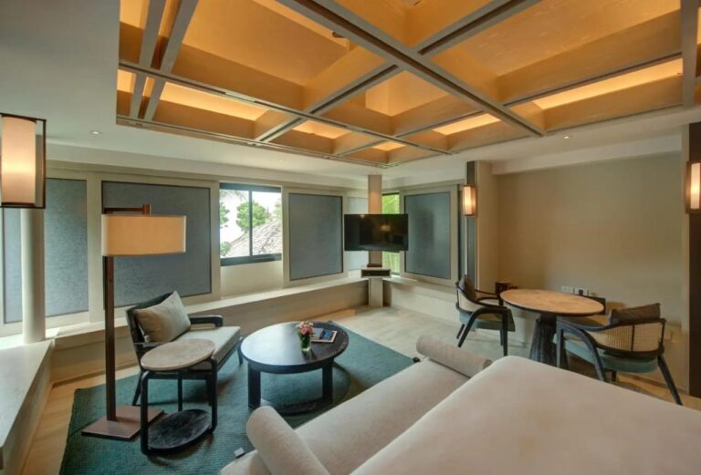 Le coin salon d'une chambre, avec un fauteuil, une table basse ronde et une table pour deux