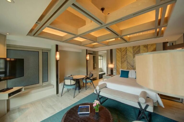 Une chambre au grand lit avec une table pour deux près de la fenêtre et un téléviseur