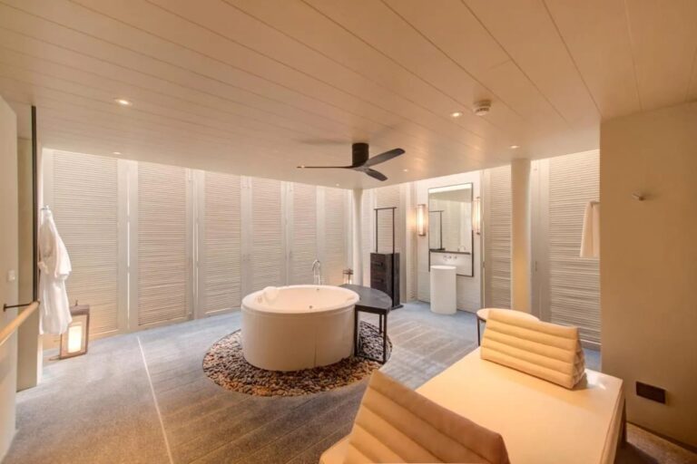 Une salle de bains du Layana Resort avec une baignoire ronde sur des galets et un peignoir suspendu