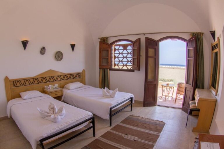 Une chambre à deux lits ouverte sur une terrasse, face à la plage et à la mer