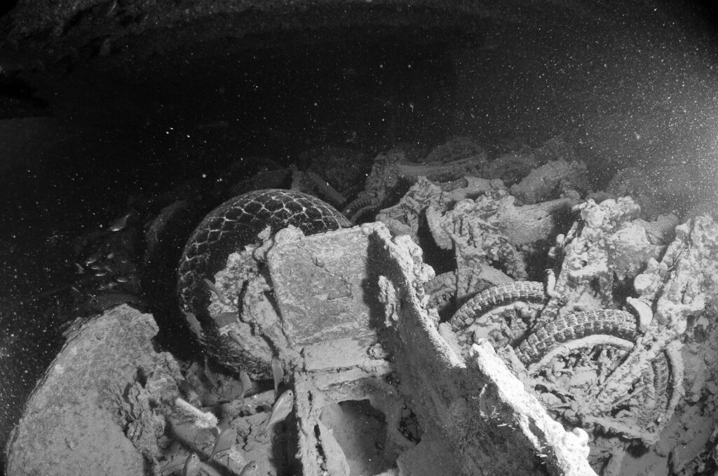 Motos empilées dans la cale du Thistlegorm, photo en noir et blanc, pneus et roues encore visibles