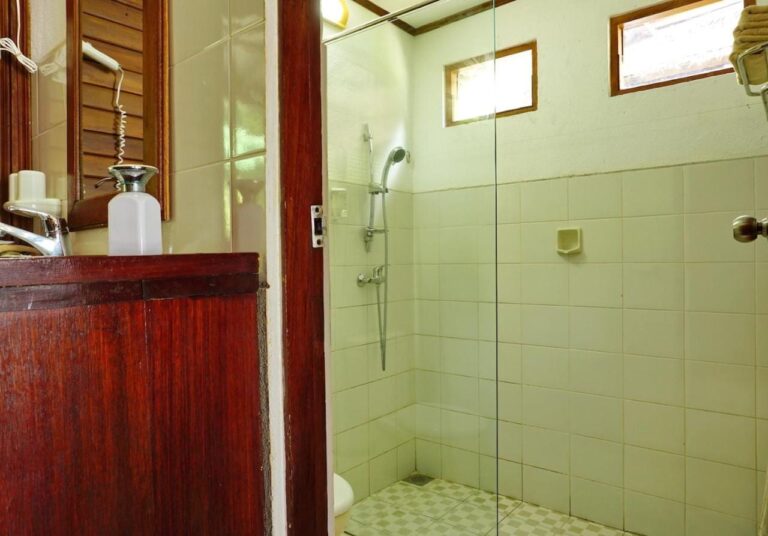 Une salle de bains avec un meuble en bois et une douche derrière une paroi vitrée