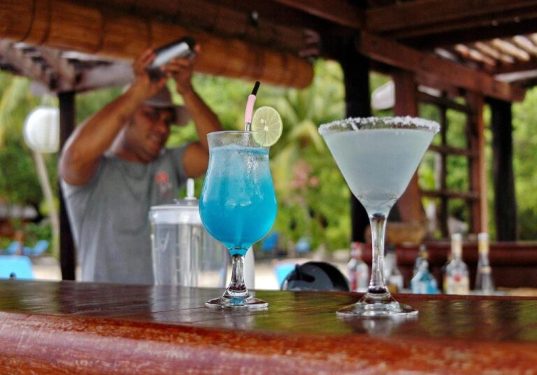 Deux cocktails, l'un bleu, sur le comptoir en bois du bar, devant le barman