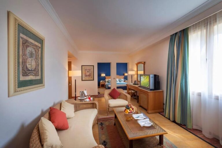 Un salon meublé en rotin, avec une chambre au mur bleu au fond