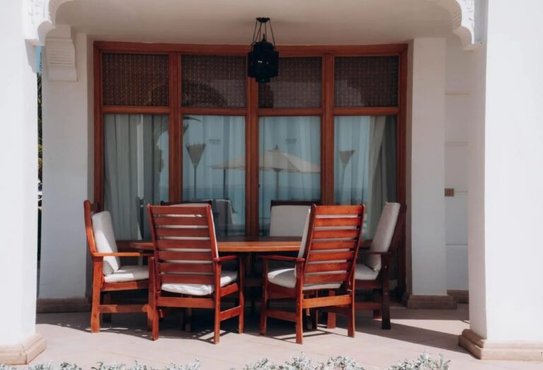Une terrasse couverte avec une table en bois et six chaises, sous une lanterne