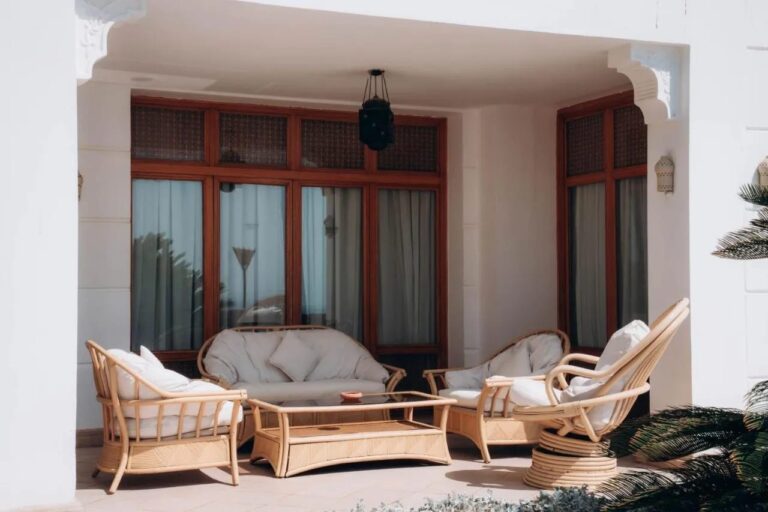 Une terrasse couverte avec un canapé et des fauteuils en rotin