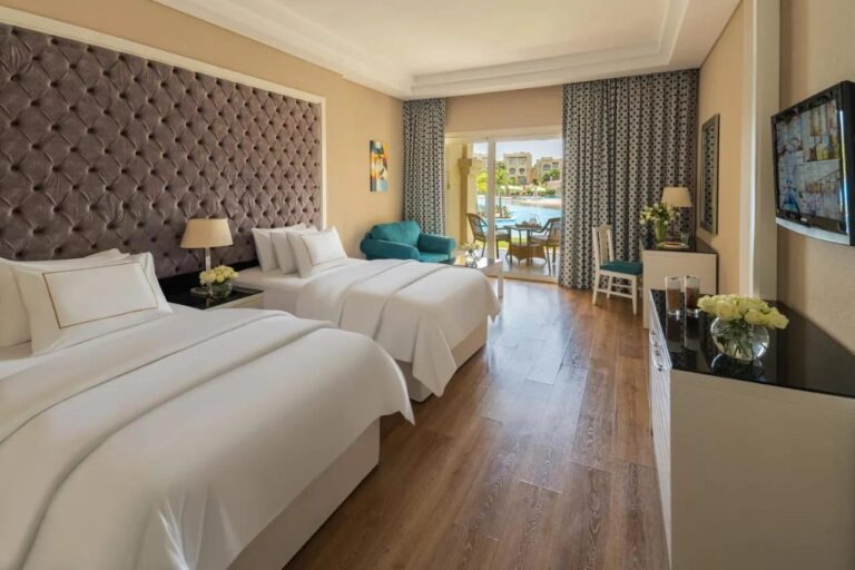 Une chambre à deux grands lits avec parquet, ouverte sur la piscine