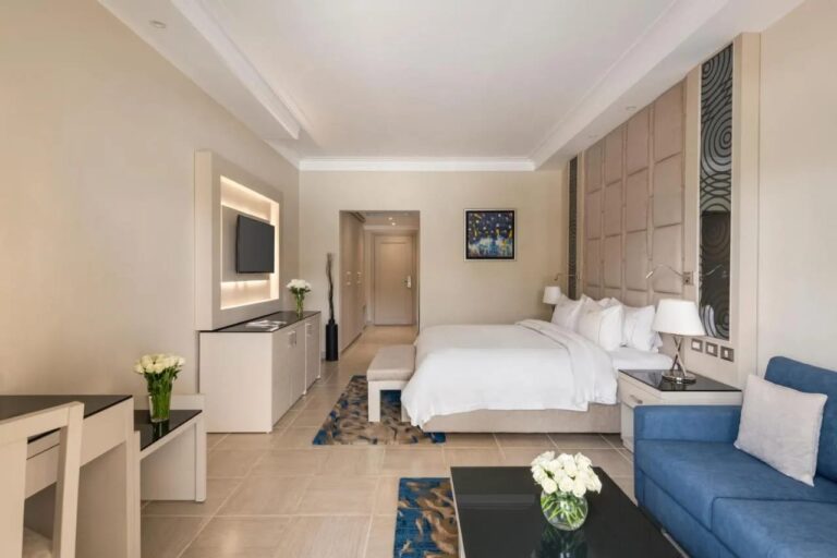 Une chambre au grand lit avec un canapé bleu et une télévision murale