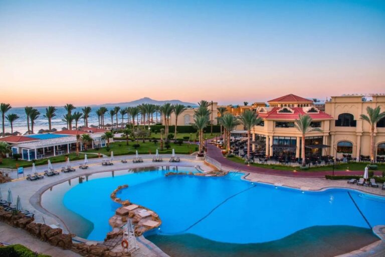 La grande piscine du Rixos Sharm El Sheikh au coucher du soleil, devant les palmiers et les montagnes du Sinaï