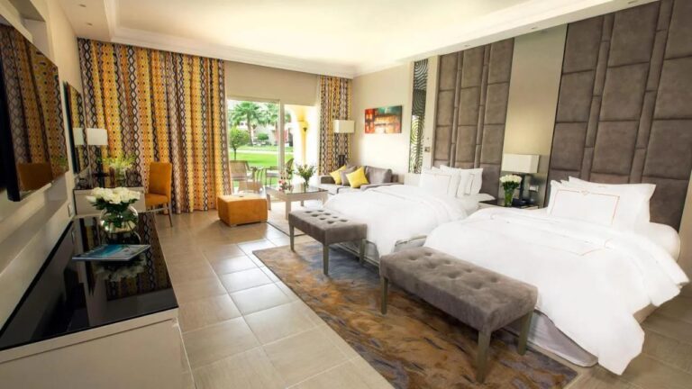 Une chambre à deux lits ouverte sur le jardin, avec des banquettes au pied des lits
